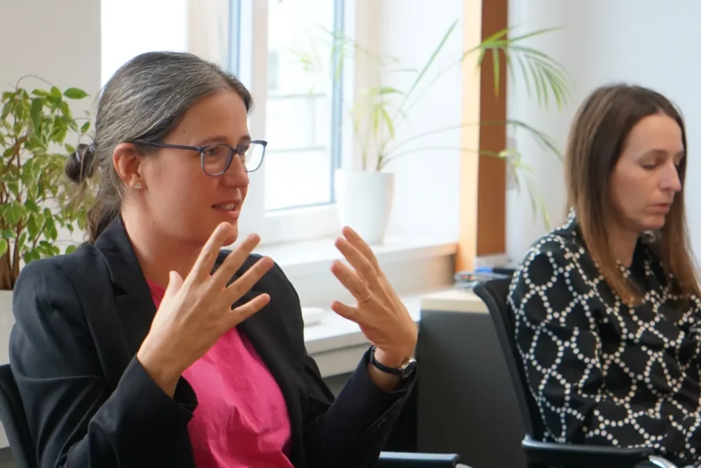 Teilnehmerin spricht engagiert in einer Workshop‑Diskussion an einem Konferenztisch.